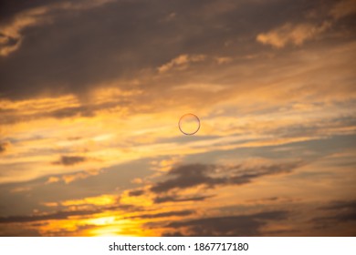Single soap bubble flying at the dramatic cloudy sunset sky.