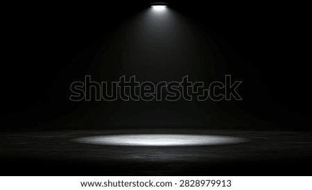 A single spotlight shines down on a dark stage floor, creating a bright circle of light with a textured surface.