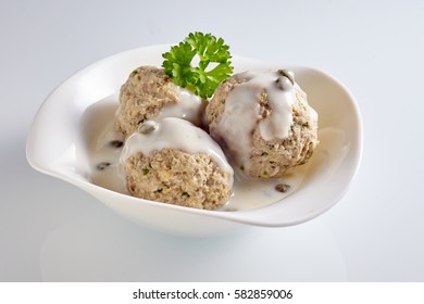 Single Sprig Of Parsley Garnish On Meatballs In Unusual Shaped Bowl. In German It Called Königsberger Klopse.