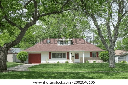 Single Story House with Red Accents Surrounded by Large Trees