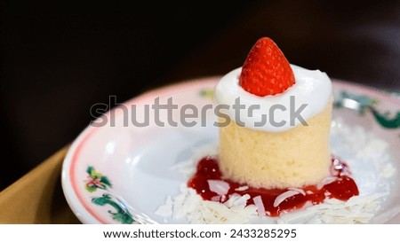 A single strawberry shortcake with whipped cream on a floral plate garnished with strawberry sauce and shredded coconut sweet dessert dish menu