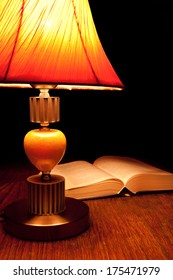 Single table-lamp and opened book in the dark room