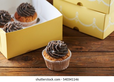 Single Tasty Chocolate Cup Cake With Paper Box Over Wooden Background