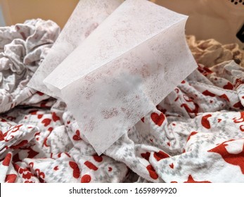Single textured fabric softener dryer sheets inside dryer with red and white heart and reindeer flannel sheets