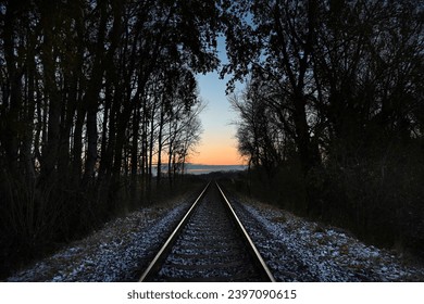 Single train track through the forest at dawn with light snow on the ground in early December