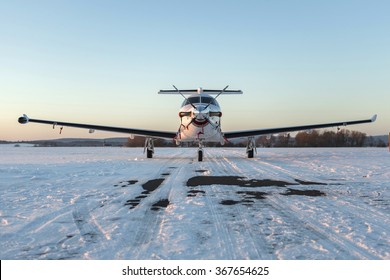 Single turboprop aircraft on winter runway at sunset time. Pribram airport. Czech Republic