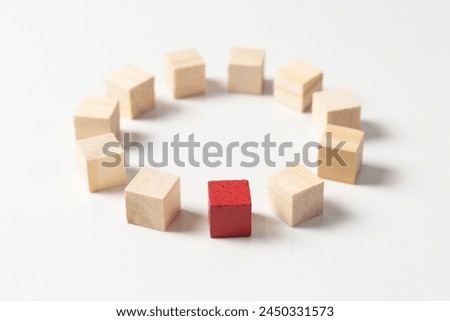 Single unique red wood block arranged in among other wooden cube blocks in round circle, concept of unique, different, diversity, outstanding, standout or talent