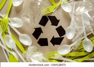 Single use, Disposable tableware and recycling sign on background. Spoons, forks. Plastic pollution. Plastic processing problem and ecological material, eco, ecology, recycle. Zero waste.   Flat lay. 