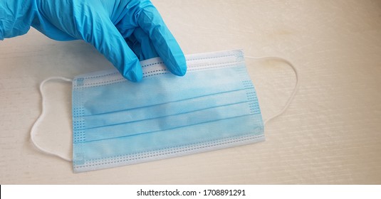 Single Use Face Protection Mask In A Hand Wearing Blue Nitrile Glove