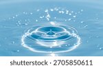 A single water drop is captured mid-fall, creating concentric ripples on a smooth, bright blue liquid surface. Numerous small, bright bokeh lights are scattered across the surface.