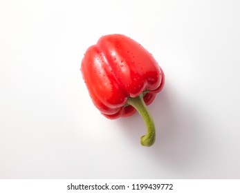 Single, wet, ripe, red bell pepper with contact shadow, isolated on white background