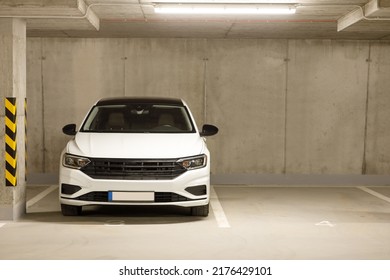 Un solo coche blanco en un aparcamiento vacío en un aparcamiento subterráneo