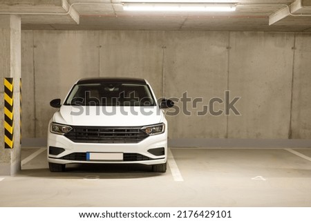 Single white car in an empty parking lot in an underground parking