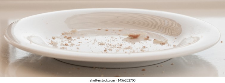 Single White Plate With Some Bread Crumbs.