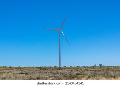 Single Wind Turbine In A Semi Arid Environment Against The Clear Blue Sky.