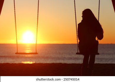 Single woman alone swinging on the beach and looking the other seat missing a boyfriend
