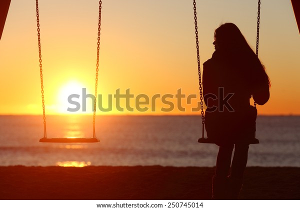 Single woman alone swinging on the
beach and looking the other seat missing a
boyfriend
