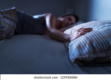 Single woman sleeping alone in bed at home. Lonely lady missing husband or boyfriend. Hand on pillow. Solitude, infidelity or heartbreak concept. Loneliness and sorrow after break up or divorce.