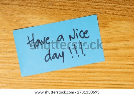 A single yellow note with the handwritten message "Have a nice day", placed on a wooden background, expressing gratitude and appreciation and wishing the best for the day