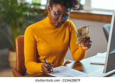 Single Young African Housewife With Many Debts Feeling Stressed, Calculating Finances, Sitting At Table With Papers, Trying To Make Both Ends Meet, Not Able To Pay Off Bills