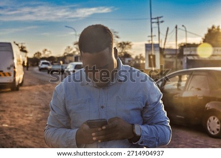 single young african men using a phone in old town at station trading area at sunrise, Johannesburg, South Africa, casual clothing