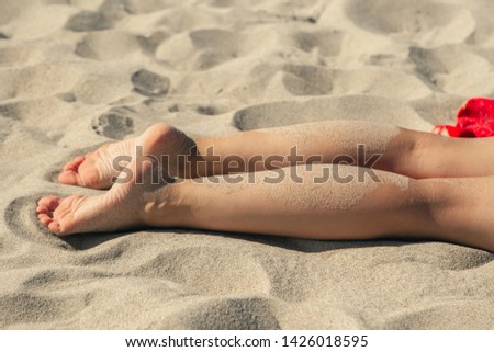 single young woman at sand sea beach tanning lying, feet closeup