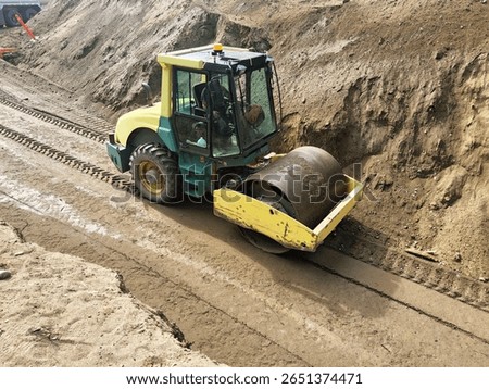 Single-drum roller compacts trench subgrade during municipal utility corridor preparation.