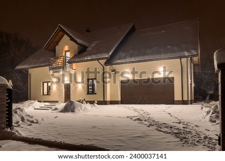 Single-family house in winter scenery at night. Lamps and lights