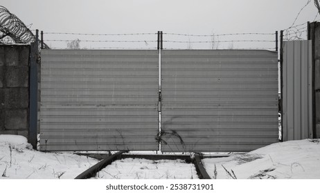 a single-track railway blocked by an iron fence and barbed wire. - Powered by Shutterstock