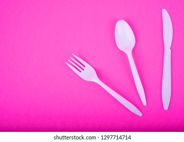 Single-Use Disposable White Plastic Polypropylene Fork, Spoon And Knife (Silverware Set) On Pink Surface, Top View. Free Copy Text Space. Legislation Against Single-use Plastics Concept. 