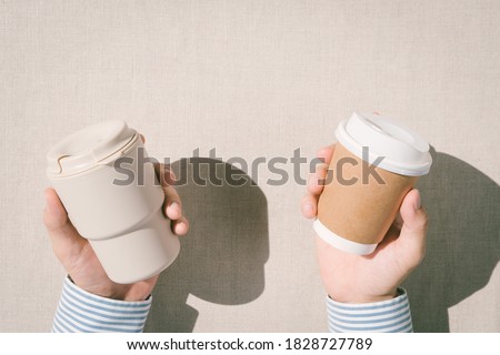 Single-Use Plastic Bans The Environment Problem issue with Disposable Coffee Cups. Top view hands of a man holding reusable cup and disposable cup with plastic lid. Environmental milestone, Zerowaste.