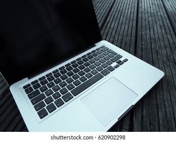 Sinister Hackers Deep Web Laptop On A Weathered Wooden Surface, Ready To Be Used For Cyber Crime, Searching The Dark Net And Writing Malware Code.