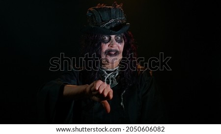 Sinister senior old mature woman in costume of Halloween witch showing thumbs down sign gesture, expressing discontent disapproval, dissatisfied, dislike. Horror theme of cosplay clown, vampire, beast
