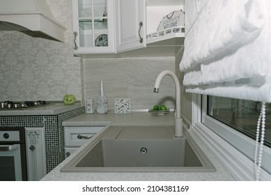 Sink made of artificial stone in the kitchen in a classic style is located near the window in the evening 
