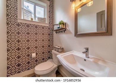 Sink toilet and mirror inside residential bathroom with decorative accent wall