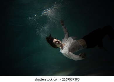 Sink. A young man is going to the bottom. A guy in a white shirt and trousers falls under the water, calmness and acceptance of fate