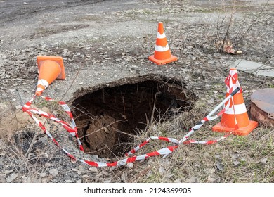 Sinkhole due to the pipe break of a main heater supply line fenced with traffic cones in the city 