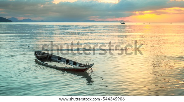 Sinking boat at\
sea against the evening\
sunset.
