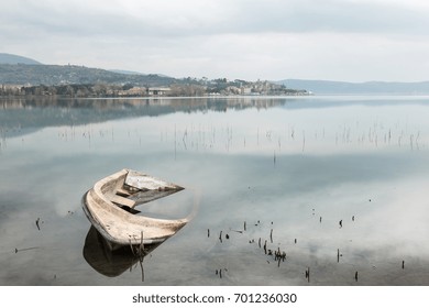 A Sinking Little Boat On Trasimeno Lake (Umbria), With Passignano Town In The Background