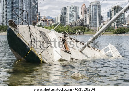Sinking sailboat abandonned on the shore of a city
