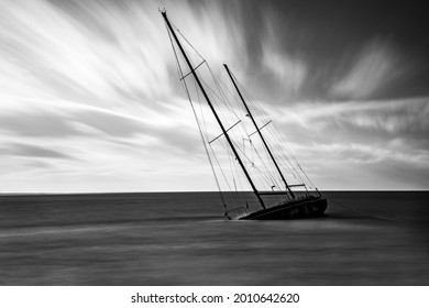 A Sinking Sailboat Close To Shore With Beautiful Wispy Clouds In The Background