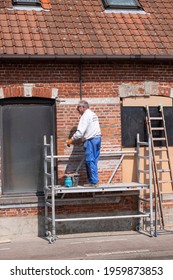 Sint Gillis Waas, Belgium, 21 April 2021, Elderly Craftsman Who Practices As A Painter Prepares The Wall Of A House For Painting