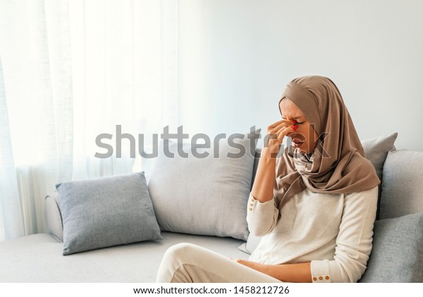 Sinus pain, sinus pressure, sinusitis. Sad Muslim
woman holding her nose and head because sinus pain. Sinus ache
causing very paintful headache. Unhealthy woman in pain. Sharp
strong sore