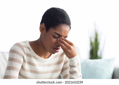 Sinusitis Concept. Sick Young Black Woman Touching Her Nose Bridge While Sitting On Couch At Home, African American Lady Feeling Unwell, Suffering From Rhinitis Or Seasonal Allergy, Free Space