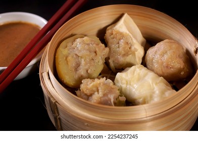 Siomay Bandung is made from wheat flour, mackerel and chopped shrimp. Some are wrapped in wonton skin, or combined with potatoes, cabbage and tofu and then steamed. Then served with peanut sauce - Shutterstock ID 2254237245