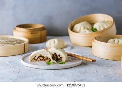 Siopao asado - filipino steamed buns with chicken filling (Cha siu bao) served on a grey background in bamboo steamer