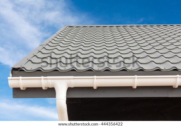 SIP panel house construction. New gray metal tile\
roof with white rain gutter