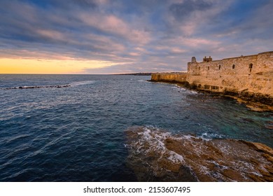 Siracusa, Italy - March 2022: Sunset over the sea with cloudy sky with Maniace Castle in Ortigia