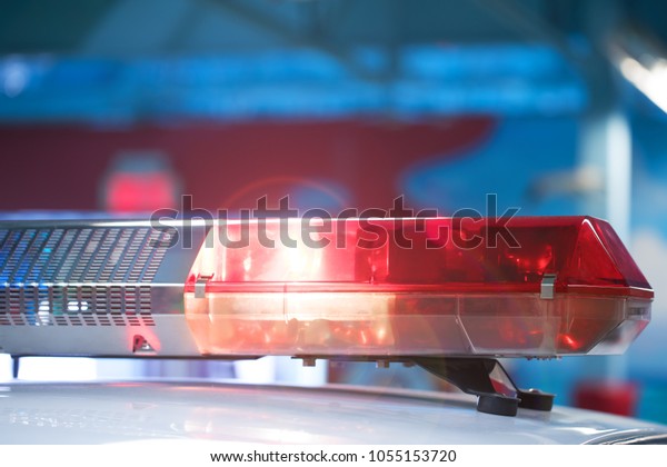Siren on police car flashing, close-up. Police\
light and siren on the car in action. Emergency flashing police\
siren in the city. Signal flasher isolated. Red siren flasher on\
the police car at night.