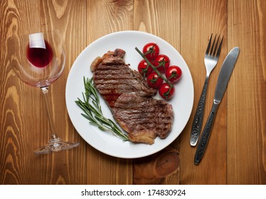 Sirloin Steak With Rosemary And Cherry Tomatoes On A Plate With Wine. View From Above